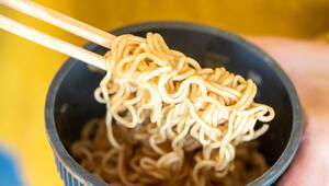 Eine Frau hält einen Becher Instantnudeln in der Hand