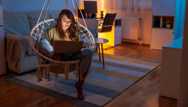 Frau sitzt nachts noch daheim am Laptop