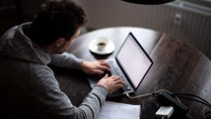 Ein Mann sitzt mit Laptop am Küchentisch