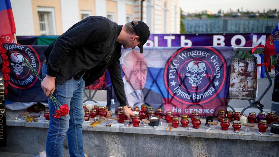 Ein Mann stellt eine Kerze neben eine informelle Gedenkstätte für die getöteten Wagner-Mitglieder