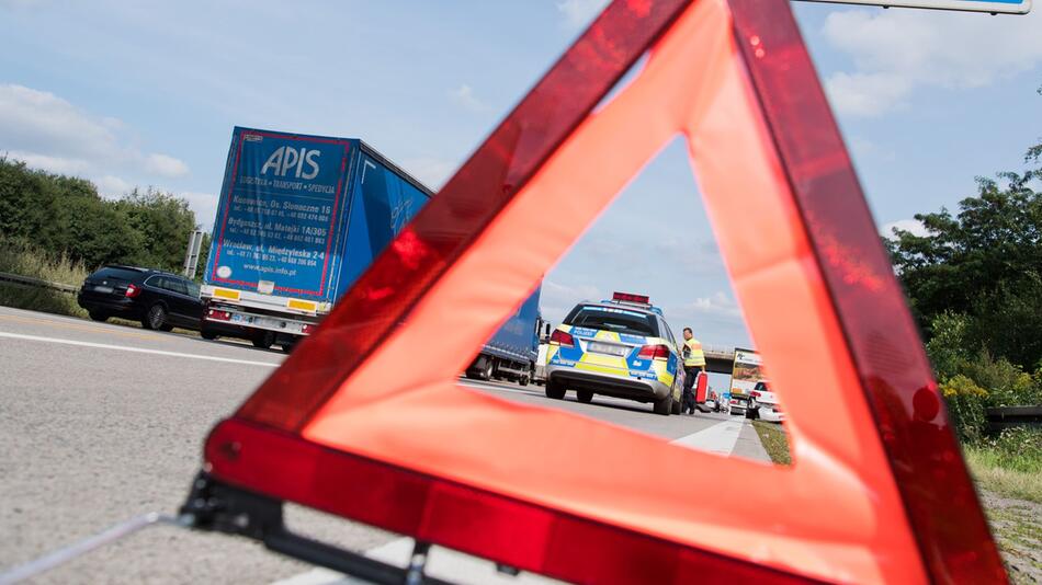 Ein Polizist sichert eine Unfallstelle hinter eihen Warndreieckab