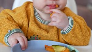Ein Kleinkind am Tisch mit Gemüse auf einem Teller
