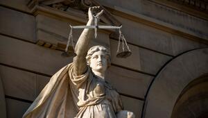 Vor einem Gerichtsgebäude steht die Statue einer Justitia