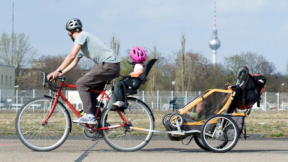 Mann transportiert Kinder mit dem Fahrrad und einem Anhänger
