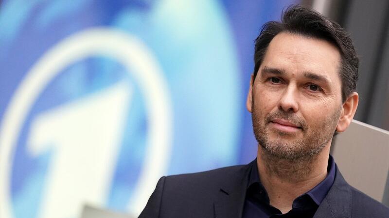 Marcus Bornheim, Chefredakteur von ARD-aktuell, steht vor dem Logo der Tagesschau.