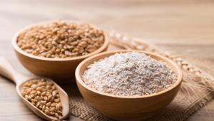 Vollkornmehl mit Weizenkorn in Schüssel auf hölzernem Hintergrund