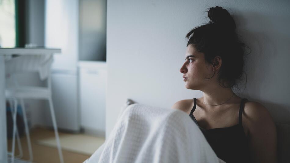 Frau, die ernst schaut und auf der Couch sitzt.