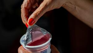 Eine Frau öffnet einen Becher Kirschjoghurt