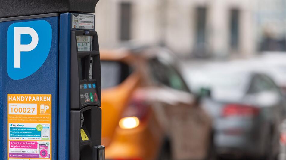 Parkscheinautomat steht vor parkenden Autos am Strassenrand