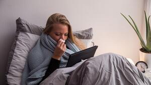 Eine Frau mit Tablet liegt krank im Bett