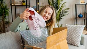 Junge Frau freut sich über ein neu gekauftes Paar Turnschuhe