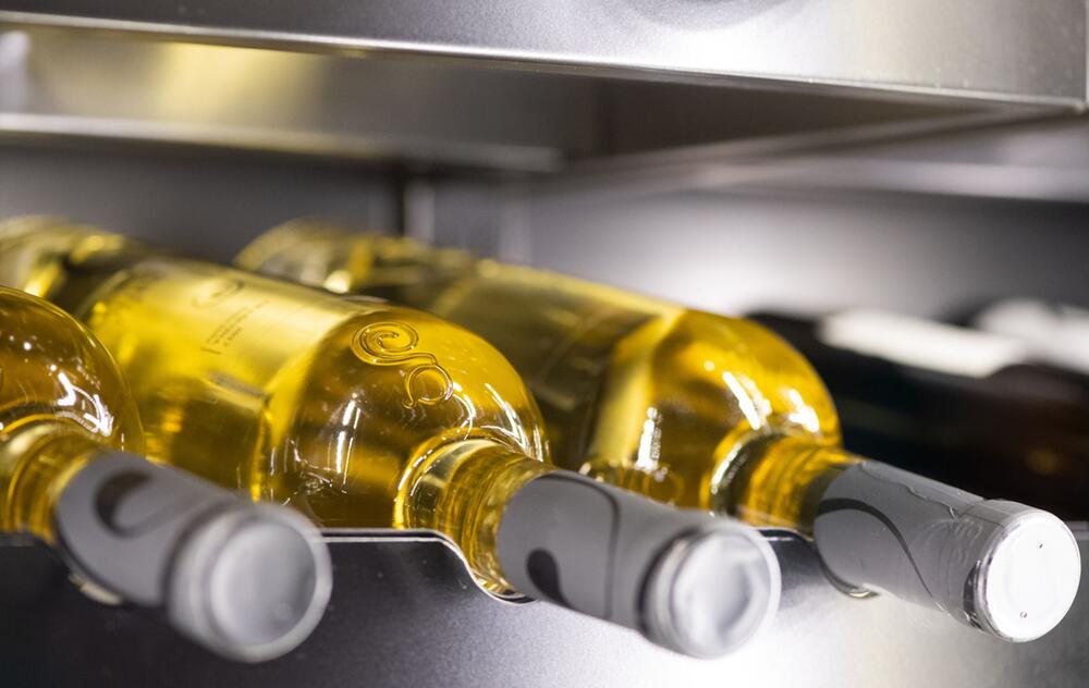 Weissweinflaschen liegen in einem Weinkühlschrank