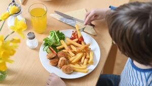 Ein Kind isst Chicken Nuggets und Pommes Frites