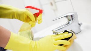 Eine Frau putzt das Waschbecken mit Reinigungsmittel