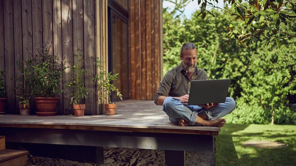 Ein Mann arbeitet am Laptop auf einer Terrasse
