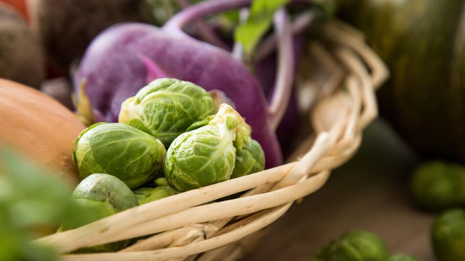 Rosenkohl und violetter Kohlrabi liegen in einem Korb