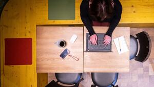 Frau sitzt im Homeoffice am Küchentisch und arbeitet am Laptop