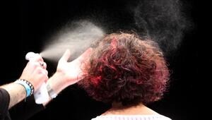 Ein Friseur sprüht einer Frau die Haare mit Haarspray ein