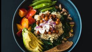 Blaue Schüssel mit Quinoa, gerösteten Kichererbsen, gehackten Zwiebeln, Avocadoscheiben ...