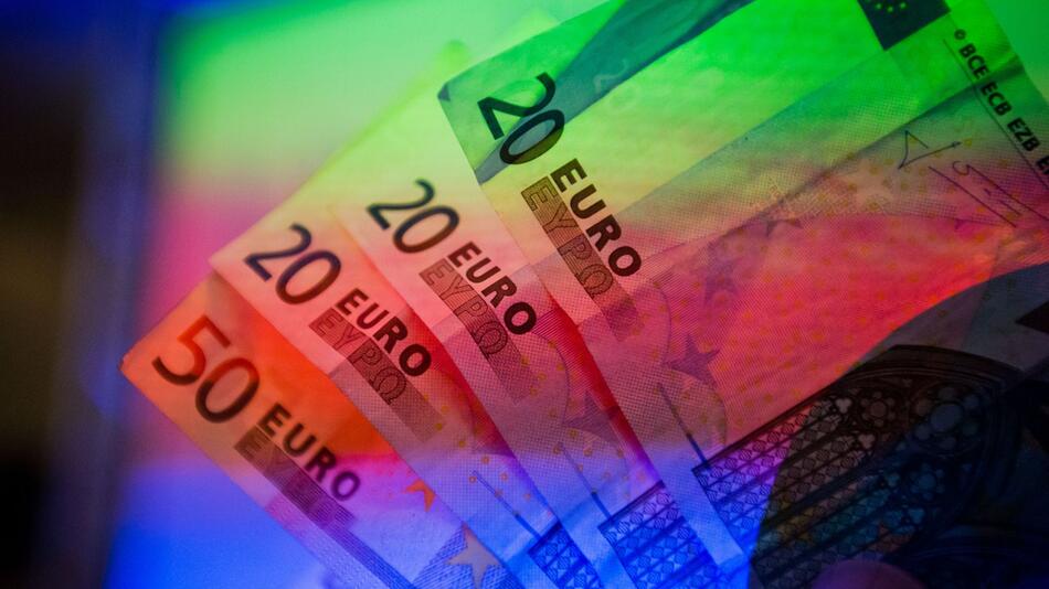 Geldscheine werden von einem Beamer farbig beleuchtet