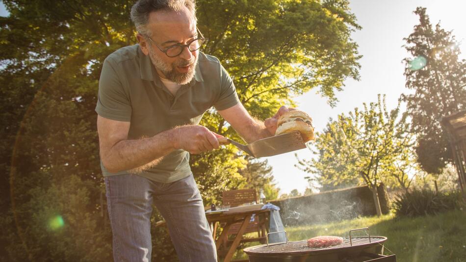 Ein Mann grillt Burger