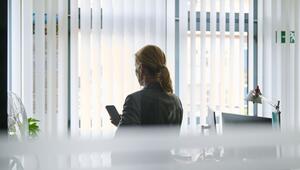 Frau steht in einem Bürozimmer am Fenster und telefoniert