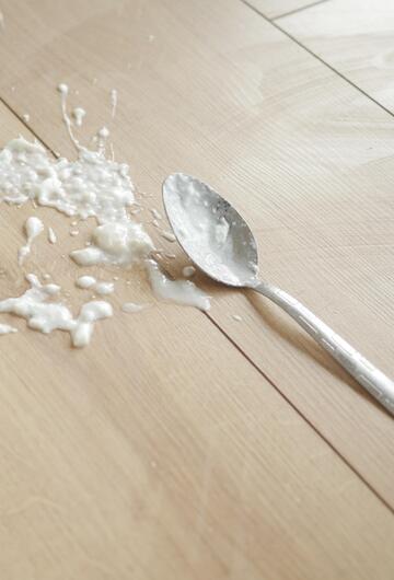 Joghurt und Löffel liegen auf dem Boden