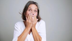 Eine ältere Frau hält eine Hand vor ihren Mund.