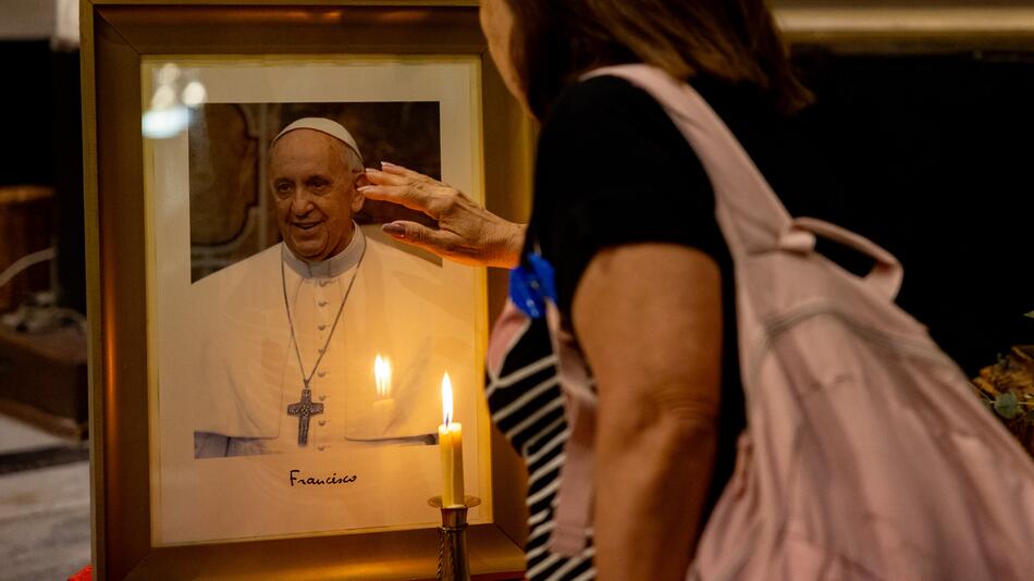 Eine Frau berührt ein Foto von Papst Franziskus.