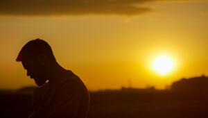 Silhouette eines Mannes mit Bart vor einem orangefarbenen Sonnenuntergangshimmel.
