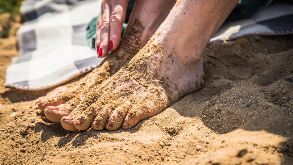 Sandige Frauenfüsse am Badesee