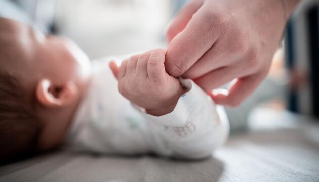 Baby hält die Hand der Mutter fest