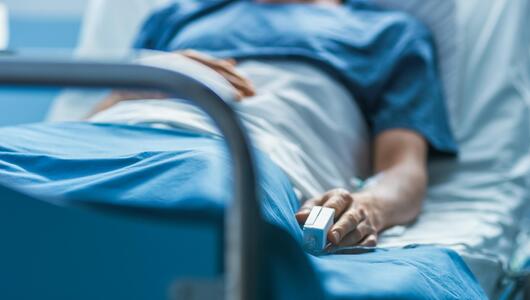 Patient in Krankenhausbett mit Pulsoximeter am Finger