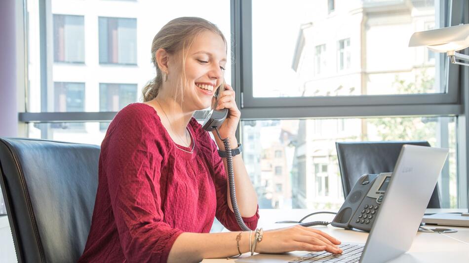 Eine Frau telefoniert und arbeitet am Laptop im Büro