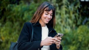 Eine Frau schaut auf ihr Handy und lacht.